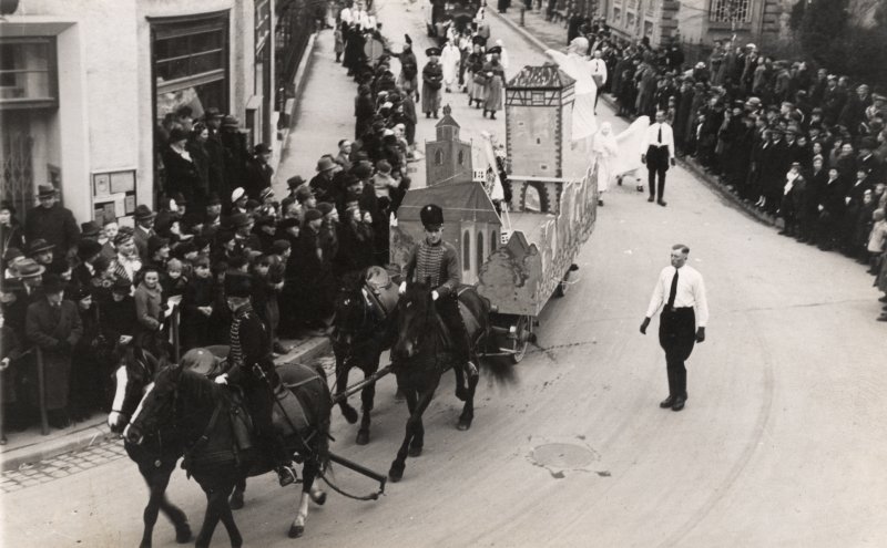 Historisches Fest: Pferde ziehen Wagen mit Figuren durch Menschenmenge. Festumzug.