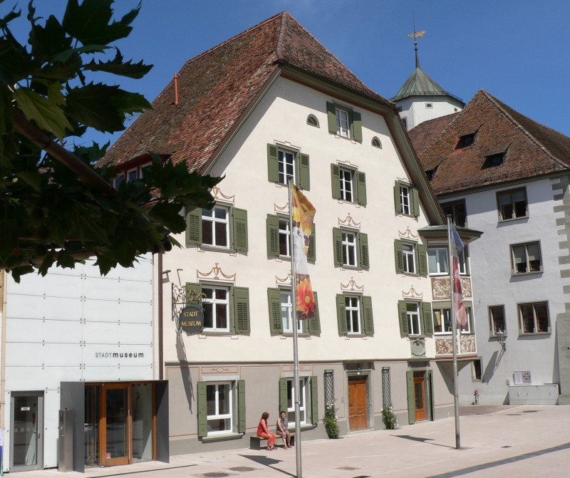 Stadtmuseum Gebäudeansicht mit grünen Fensterläden und Flaggen. Sehenswürdigkeit und Kultur in historischer Architektur.